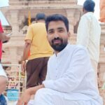 महिदपुर रोड के एक मंदिर परिसर में संतोष विश्वकर्मा श्रद्धालुओं के साथ खड़े, पारंपरिक परिधान में, सेवा और समर्पण का प्रतीक दृश्य