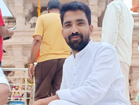 महिदपुर रोड के एक मंदिर परिसर में संतोष विश्वकर्मा श्रद्धालुओं के साथ खड़े, पारंपरिक परिधान में, सेवा और समर्पण का प्रतीक दृश्य