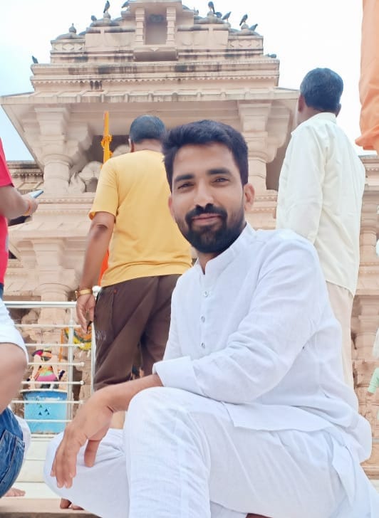 महिदपुर रोड के एक मंदिर परिसर में संतोष विश्वकर्मा श्रद्धालुओं के साथ खड़े, पारंपरिक परिधान में, सेवा और समर्पण का प्रतीक दृश्य