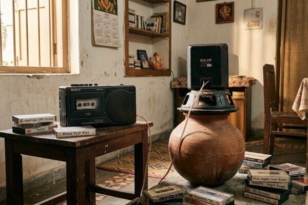 “1990 के दशक का भारतीय घर जिसमें टेपरिकार्डर, कैसेट और मटके पर रखा स्पीकर देसी जुगाड़ साउंड सिस्टम के रूप में इस्तेमाल हो रहा है”