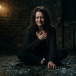 अकेला व्यक्ति अपने टूटे दिल और भावनात्मक दर्द के साथ अंधेरे में बैठा हुआ