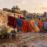 पुरानी छत पर सूखते कपड़े, दर्पण और बिखरे फूलों के साथ यादों से भरा भावनात्मक दृश्य