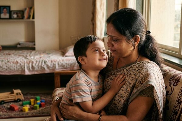 डाउन सिंड्रोम से ग्रस्त बच्चे को प्यार से गोद में लिए एक माँ का भावनात्मक दृश्य