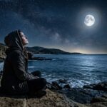 अकेला व्यक्ति चाँदनी रात में बैठा, उदासी और यादों में खोया हुआ