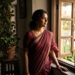 खिड़की के पास खड़ी एक महिला, बंधनों से आज़ादी की ओर बढ़ती हुई