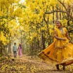 अमलतास के सुनहरे फूलों से भरे जंगल में पीले घाघरे पहने रंगरेजन का जादुई और प्रकृतिमय दृश्य।