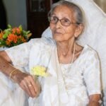 रसोई में आम पापड़ बनाती हुई माँ और पास बैठा बच्चा, बचपन की यादों और ममता को दर्शाता भावुक दृश्य।