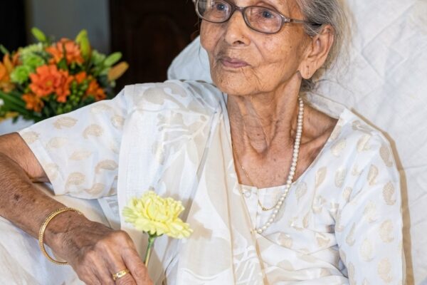 रसोई में आम पापड़ बनाती हुई माँ और पास बैठा बच्चा, बचपन की यादों और ममता को दर्शाता भावुक दृश्य।