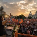 कोलकाता में आयोजित एक विशाल चुनावी रैली का दृश्य, जहाँ बड़ी संख्या में लोग राजनीतिक झंडों और बैनरों के साथ नेताओं का संबोधन सुन रहे हैं। चुनावी माहौल, जनउत्साह और लोकतांत्रिक गतिविधियों को दर्शाता यथार्थवादी चित्र।