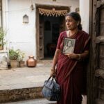 मायके के दरवाज़े पर खड़ी एक भावुक बेटी, माँ की तस्वीर को देखते हुए बीते दिनों को याद करती हुई।