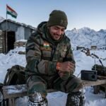 लद्दाख की सरहद पर तैनात सैनिक अपनी कलाई पर लाल धागा बाँधता हुआ